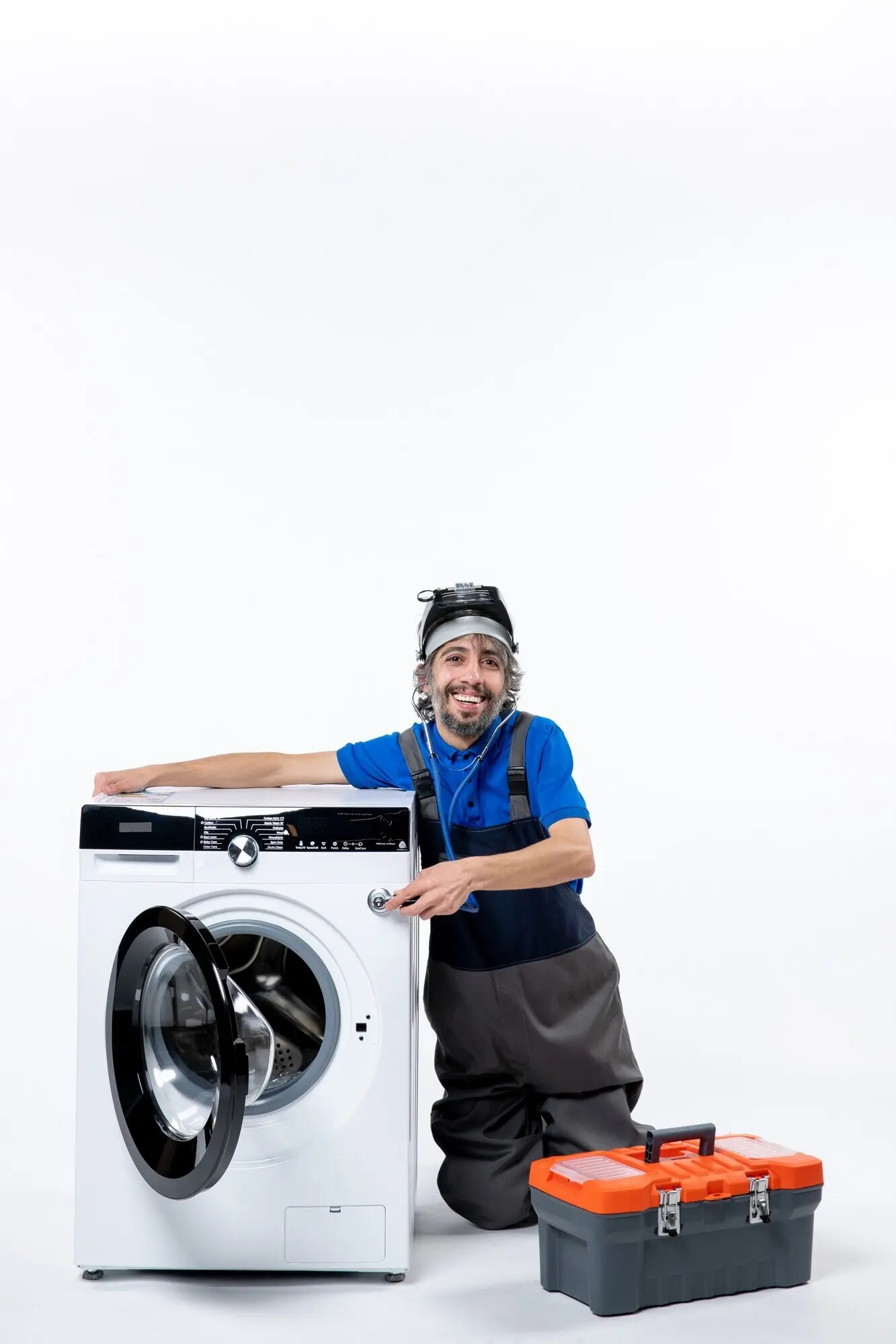 Vorderansicht eines fröhlichen Reparaturtechnikers, der eine Waschmaschine hält, vor weißem Hintergrund.